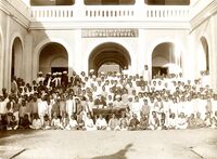 A group of students seated with a building in the background.