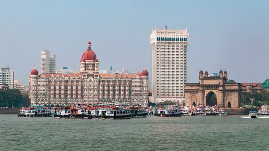 Mumbai, the centre of India's tertiary sector finance industry, also contributes to tourism. Shown here are the Taj Mahal Palace Hotel to the left and the Gateway of India.
